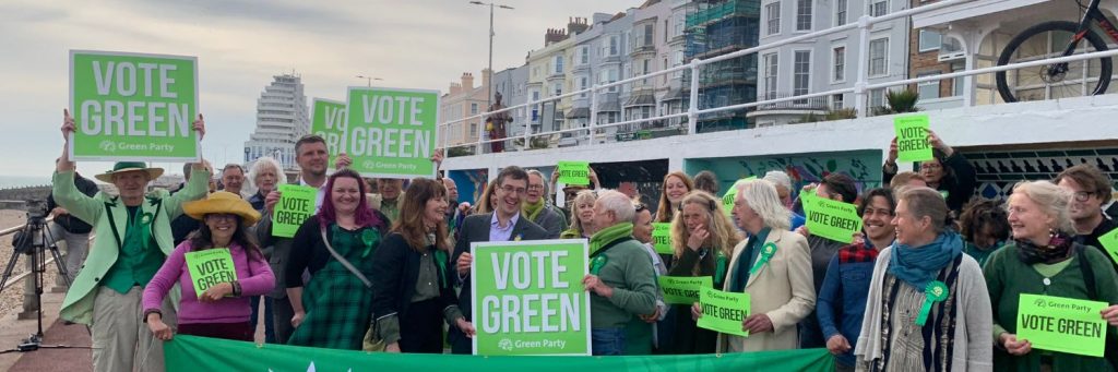 A group of people holding banners which read 'Vote Green'